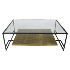 a glass and metal coffee table with a gold rug on the bottom, against a white background