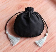 a small black bag with tassels sits on a wooden surface