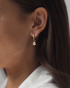 a woman wearing a pair of gold and white earrings with pearls on the end of each ear