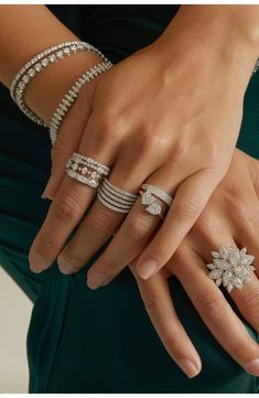 a woman's hands with rings and bracelets on their fingers, both wearing green dresses