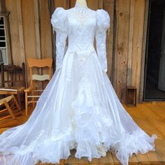 a white wedding dress on display in front of a wooden wall