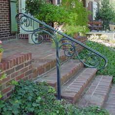 an iron hand rail on the steps leading up to a brick house with potted plants