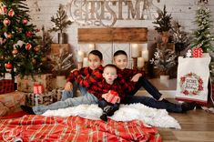 two children sitting on the floor in front of christmas decorations