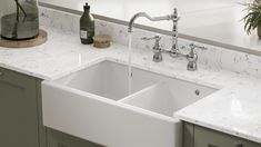 a white kitchen sink sitting under a faucet next to a counter top with bottles