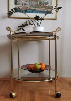 a glass table with some fruit on it and a painting hanging above the table behind it