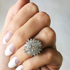 a woman's hand holding a ring with white and beige nail polish on it