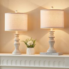 two white lamps sitting on top of a mantle