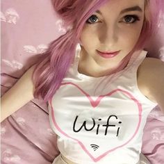 a woman with pink hair laying in bed wearing a white shirt that says wifi