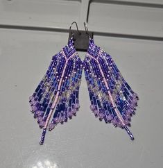 Hand Beaded 15/0 Seed Bead Earings with Amethyst Fringe 🔮💜 How can Amethyst benefit me? As a mediation stone it helps quite the mind and is an aid to finding deep inner peace and discovering the wisdom residing in ourselves. It clarifies the inner world of images and also our dream lives. Emotionally, amethyst will help in sadness and grief and lend support in coming to terms with loss. Amethyst encourages sobriety and awareness. #Amethyst should be worn close to the body, for a long period of time or contemplated steadily during regular Meditations. Purple Spiritual Beaded Jewelry, Spiritual Purple Beaded Jewelry, Purple Long Drop Beaded Earrings With Dangling Beads, Purple Dangle Beaded Earrings With Spacer Beads, Artisan Earrings With Polished Beads For Gift, Artisan Polished Beads Earrings As Gift, Artisan Polished Beads Earrings For Gift, Purple Beaded Teardrop Earrings With Ear Wire, Beaded Earrings With Round Beads For Gifts