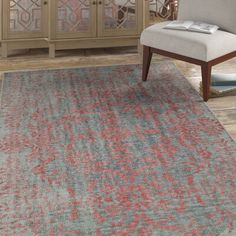 a living room area with a chair, rug and cabinet in the background on hardwood flooring