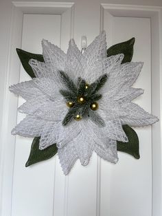 a white and green christmas wreath hanging on a door