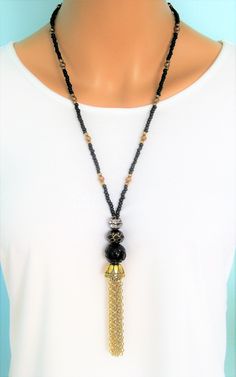 Bohemian Style black and gold beaded necklaces, handmade by Ralston Originals. These beautiful tassel necklaces come in your choice of 3 different Styles. I made the tassels with gold metal chain, and a large antique gold cap. I made the first necklace (pictures 1-3), with a large black bead with gold metal dots, and a black bead with gold stripes. The beaded chain is made with black seed beads, and gold acrylic beads. This necklace is 28 inches long, and has a lobster clasp. I made the second n Black Tassel Necklace With Adjustable Fit, Elegant Long Necklace With Beaded Chain For Festivals, Elegant Long Beaded Chain Necklace For Festivals, Adjustable Black Tassel Necklace, Black Tassel Jewelry For Festival, Elegant Black Tassel Necklace, Black Tassel Necklaces As Gift, Black Tassel Necklace As Gift, Black Tassel Necklace Gift