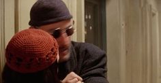 a man and woman hugging each other in front of an open door, wearing knitted hats