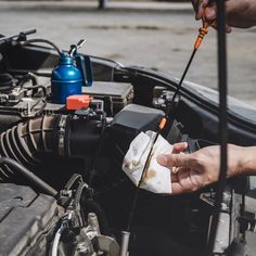 a man is working on an engine in his car while another person holds the wrench