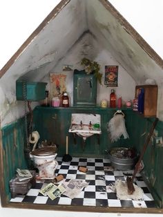 a dollhouse kitchen with black and white checkered flooring, green cupboards and cabinets