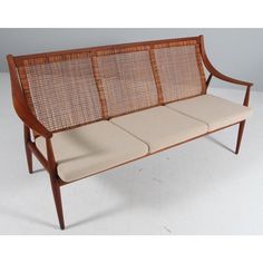 a wooden bench with four seats on it's back and armrests that have woven upholstered cushions