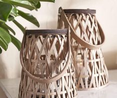 two wooden lanterns sitting on top of a table next to a potted green plant