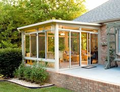 an enclosed patio with glass walls and brick steps leading up to the back of the house