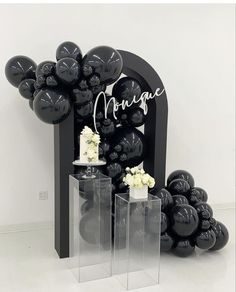 black balloons and white flowers are arranged in front of an arch with the word marriage written on it