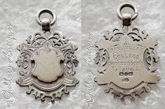 two silver metal tags with ornate designs on white paper and one has an oval shaped tag