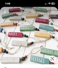 colorful wooden christmas signs hanging from string on white wood planks with beaded garland