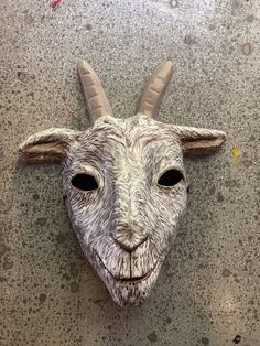 a goat mask with long horns on the ground next to paint splattered walls