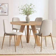 a dining table with four chairs and a vase on the top, in front of a white wall