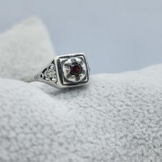 This vintage Joe Espisito ring is a stunning piece of jewelry that will make any occasion special. The ring is made of sterling silver and features a beautiful blood red garnet stone. The filigree design adds a touch of elegance to the ring, making it perfect for a formal event or a day at the beach. The ring is a size 5.25 and is signed by the artist. It is a unique piece that will make a great addition to any collection. Whether you are buying it as a gift or for yourself, this ring is sure to impress. Thank you for considering our merchandise! All items are described to the best of our knowledge. Vintage and antique pieces may show signs of wear consistent with their age.  Note there may be reflections, if any, from the camera or lights. Please look carefully at all the photos as they a Vintage Sterling Silver Engraved Signet Ring, Vintage Gemstone Signet Ring, Vintage Engraved Sterling Silver Signet Ring, Vintage Round Gemstone Signet Ring, Vintage Ruby Ring With Polished Finish, Vintage White Gold Open Ring, Vintage White Gold Birthstone Ring, Vintage Red Hallmarked Signet Ring, Vintage White Gold Gemstone Ring