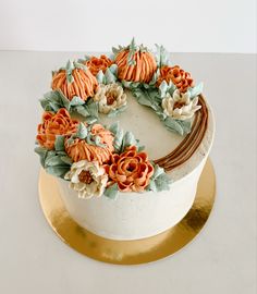 a white cake with orange and blue flowers on it sitting on a gold platter