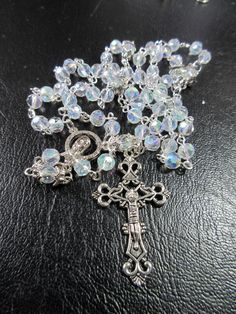 "This Catholic rosary is made of clear Aurora Borealis crystals. It is a complete 5 decades and a good gift for First Communion or a Baptism. The body is 26\" around and the cross drop is 5 inches. The rosary will be slipped into a velvet bag and shipped in a bubble mailer." Silver Beaded Rosary For First Communion, Silver Rosary Bracelet With Round Beads For Baptism, Silver Spiritual Jewelry For First Communion, Spiritual Silver Jewelry For First Communion, Spiritual Silver Rosary As Gift, Silver Faceted Beads Rosary Cross, Silver Beaded Jewelry For Baptism, Silver Jewelry With 8mm Beads For First Communion, Silver Rosary With Miraculous Medal And Round Beads