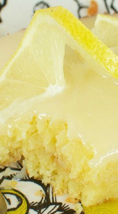 a slice of lemon cake with icing on a yellow and white plate next to a fork