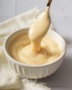 a spoon full of mayonnaise sitting in a white bowl