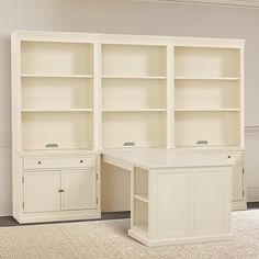 an empty room with two white bookcases and a desk in the middle is shown