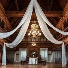 a large room with white draping and chandelier hanging from the ceiling