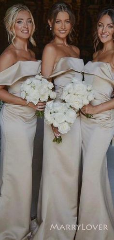 three bridesmaids pose for a photo in their wedding gowns and bouquets