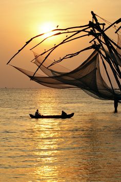 two people in a small boat on the water with fishing nets attached to their sails