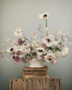 a vase filled with lots of flowers sitting on top of a wooden table