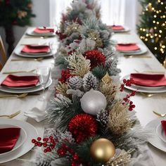 the table is set for christmas dinner with silver and red decorations on top of it