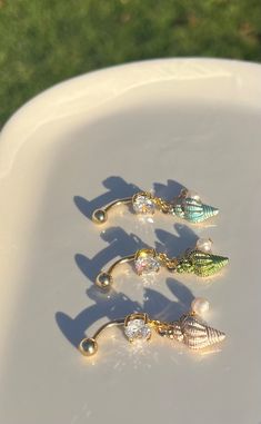 three different types of earrings sitting on top of a white plate with grass in the background