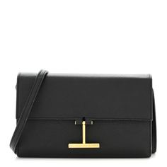 This is an authentic TOM FORD Calfskin T Clasp Tara Wallet On Strap in Black. This petite shoulder bag is crafted of grained calfskin leather in black. The bag features a leather crossbody strap with gold hardware and a decorative Upside down T emblem on the front flap.  This opens to a black leather interior with a zipper compartment, flat pocket, and card slots. Black Leather Wallet On Chain For Business, Black Wallet On Chain With Gold-tone Hardware For Business, Elegant Tan Wallets For Business, Black Business Wallet On Chain Crossbody, Black Crossbody Wallet On Chain For Business, Leather Clutch Wallet On Chain For Business, Modern Black Wallet On Chain For Business, Black Evening Bags With Grained Texture, Elegant Black Shoulder Bag With Grained Texture