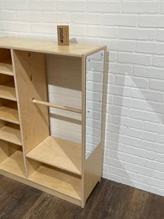 an empty wooden shelf next to a white brick wall and wood floored flooring