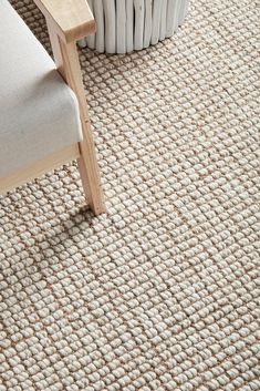 a white chair sitting on top of a rug next to a wooden table