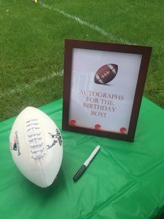 an autographed football sits on a green table with a framed photo and pen