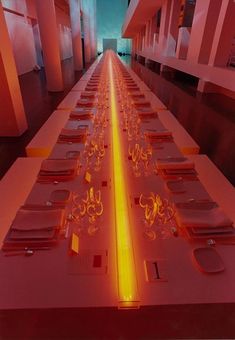 a long table with many place settings on it in a room that has red walls and flooring