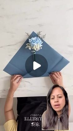 a woman holding up a piece of paper with flowers on it and the video below