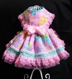 a pink dress with butterflies on it is sitting on a white metal stand in front of a black background