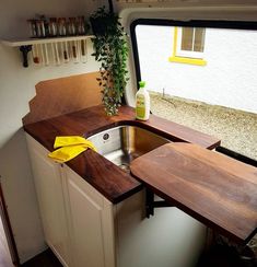 a kitchen area with sink, counter top and shelves in an rv or camper