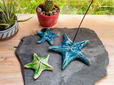 three ceramic starfishs sitting on top of a rock next to a potted plant