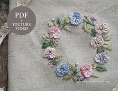 an embroidered flower wreath on a piece of linen with the words youtube video written below it