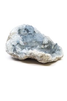 a rock that is sitting on top of a white surface with some blue crystals in it